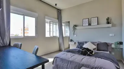 a bedroom with a bed and a table and windows at Vilamoura in Quarteira