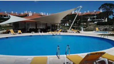 a swimming pool with a white umbrella and chairs at Casa Joanna Vila Sol Golf Village in Quarteira