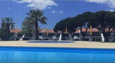 a large swimming pool with chairs and umbrellas at Casa Joanna Vila Sol Golf Village in Quarteira