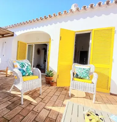 a patio with two chairs and a yellow door at Villa Blue - Aldeia do Golfe in Quarteira