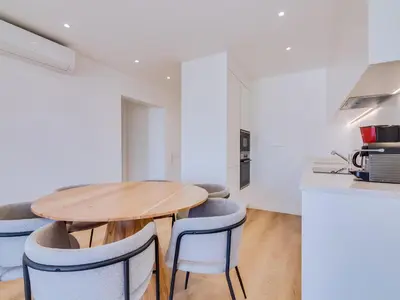 a kitchen and dining room with a wooden table and chairs at AL Apartamento Alsol in Quarteira
