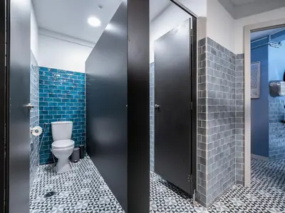 a bathroom with a toilet and blue tiles at Walk in Hostel Faro Airport in Faro