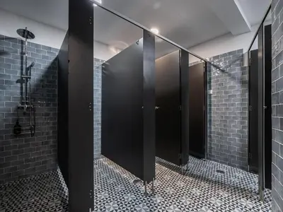 a row of stalls in a bathroom with black mirrors at Walk in Hostel Faro Airport in Faro