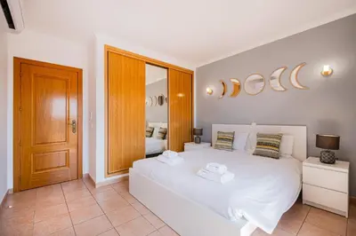 a bedroom with a white bed and a mirror at Villa Gil in Albufeira