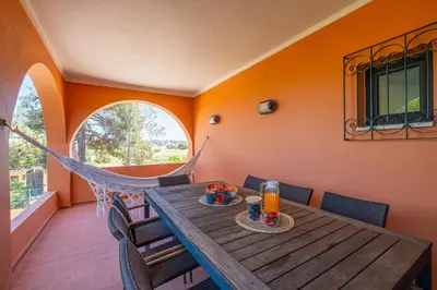 a porch with a wooden table and chairs and a hammock at Orange Tree House in Albufeira