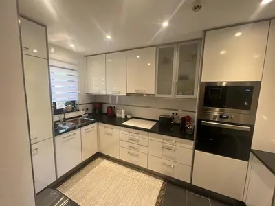 a kitchen with white cabinets and black appliances at ADO HOUSE Albufeira in Albufeira