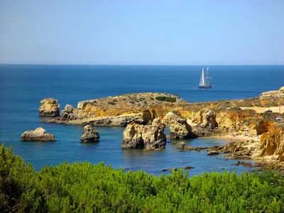 a boat in the water with rocks in the ocean at Marina Sea Residence in Albufeira