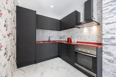 a kitchen with black cabinets and red counter tops at Casa Verde Vilamoura in Quarteira