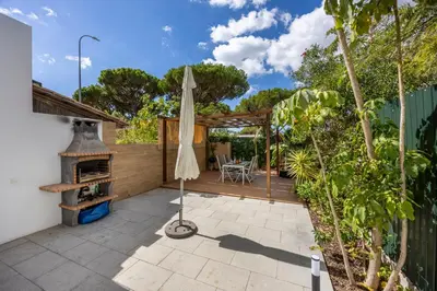 an outdoor patio with an umbrella and an outdoor oven at Casa Verde Vilamoura in Quarteira