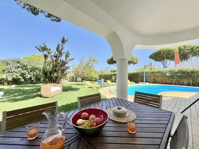 a wooden table with a bowl of fruit on a patio at Vilamoura White House Villa With Pool by Homing in Vilamoura