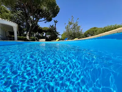 a swimming pool with blue water in front of a house at Vilamoura White House Villa With Pool by Homing in Vilamoura