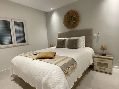 a bedroom with a large white bed and a window at Modern Apartment with balcony and direct access to the pool in Albufeira