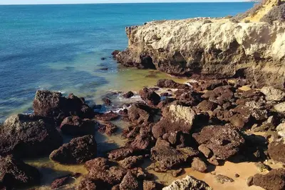 a group of rocks on a beach near the ocean at Beach Front Luxury T1 Apt Pools Garage Tennis in Albufeira