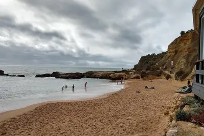 a group of people standing in the water on a beach at Beach Front Luxury T1 Apt Pools Garage Tennis in Albufeira