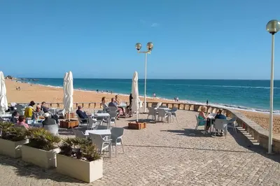 a group of people sitting in chairs on the beach at Beach Front Luxury T1 Apt Pools Garage Tennis in Albufeira