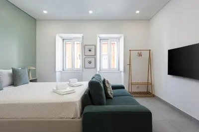 a bedroom with a bed and a couch and a flat screen tv at Casa São Francisco Old Town Faro in Faro