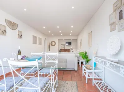 a living room with white furniture and a kitchen at Albufeira Boho Apartment in Albufeira