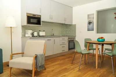 a kitchen with white cabinets and a table and chairs at Pilar Apartment in Albufeira