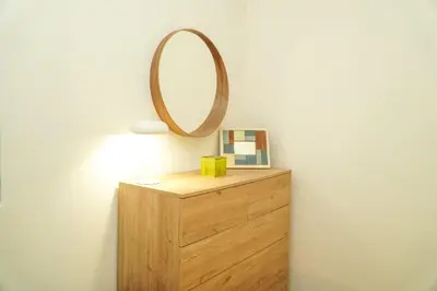a mirror on top of a wooden dresser next to a lamp at Pilar Apartment in Albufeira