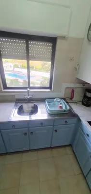 a kitchen with blue cabinets and a sink and a window at Apartment - Sleeps 2 Parking & Pool Access in Albufeira