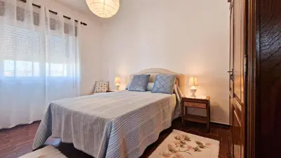 a bedroom with a bed with blue pillows and a window at Apart Alfarrobinha - T2 - BY BEDZY in Tunes