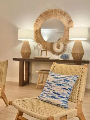 a wicker chair with a pillow in front of a mirror at Apartamentos do Atlantico in Albufeira