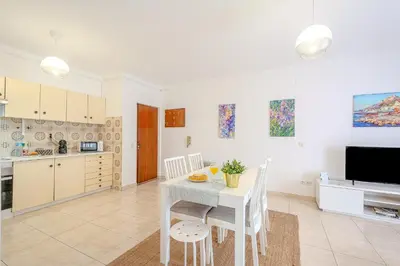 a kitchen and dining room with a white table and chairs at Apartamento Briza by Sunnyway in Albufeira