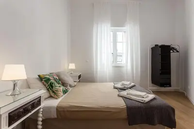 a white bedroom with a bed and a tv at Charming house with terrace near the city center in Faro