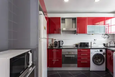 a kitchen with red cabinets and a washing machine at Charming house with terrace near the city center in Faro