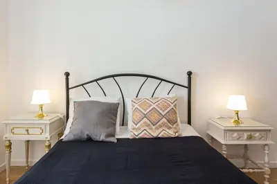 a bedroom with a bed with two tables and two lamps at Charming house with terrace near the city center in Faro