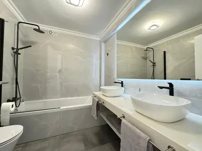 a bathroom with two sinks and a shower and a tub at Casa Coral Azul in Albufeira