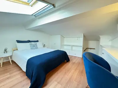 a bedroom with a bed and a blue chair at Casa Coral Azul in Albufeira