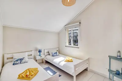 two beds in a white room with a window at T2 duplex na Marina de Vilamoura in Loulé
