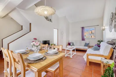 a dining room and living room with a wooden table and chairs at T2 duplex na Marina de Vilamoura in Loulé