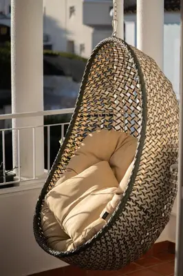 a hanging rattan hammock chair with a pillow on a balcony at Luxurious Villa - Pool, Hot Tub, Cinema and Golf in Vilamoura