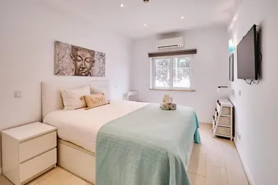 a white bedroom with a bed and a tv at Apartment Monaco mit Pool in Albufeira