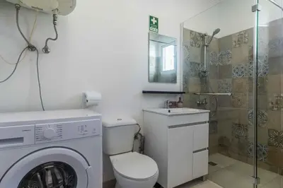 a bathroom with a washing machine and a shower at white T1 - Ocean View in Albufeira