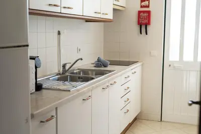 a kitchen with a sink and white cabinets at Oasis apartment - City center by HD in Faro