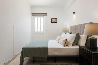 a white bedroom with a bed with pillows at Oasis apartment - City center by HD in Faro