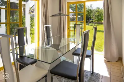 a glass dining room table and chairs with a view of a yard at Sunshine Villa Salgados Guia Algarve in Albufeira