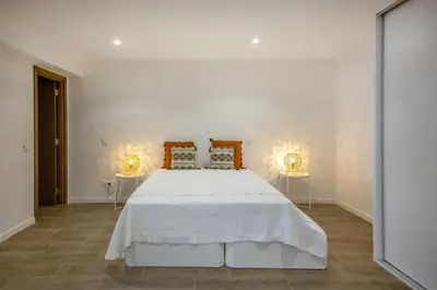 a white bedroom with a white bed with two lamps at Krystal Bay Villa in Albufeira