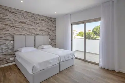 a bedroom with a white bed and a stone wall at Krystal Bay Villa in Albufeira
