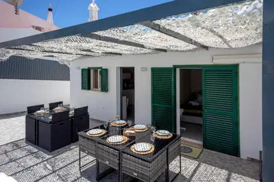 a patio with green shutters and a table with food at Villa Le petit charme in Albufeira