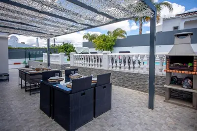 a patio with a table and chairs and an outdoor grill at Villa Le petit charme in Albufeira