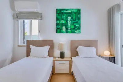 a bedroom with two beds and a green painting on the wall at Villa Andorra, private pool next to golf in Vilamoura
