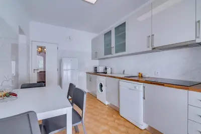 a kitchen with white cabinets and a white table with chairs at Villa Andorra, private pool next to golf in Vilamoura