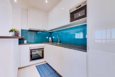 a kitchen with white cabinets and blue walls at 2bdr Sea View Miravila Apartment in Quarteira in Quarteira