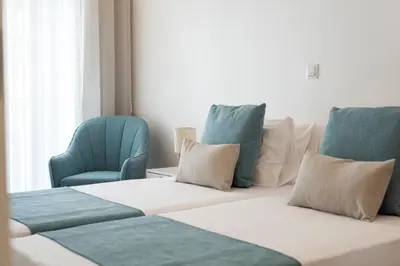 a room with two chairs and a bed with pillows at Madalena Hostel e Suites in Faro