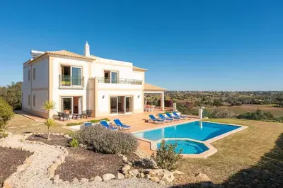 a villa with a swimming pool in front of a house at Villa Água in Albufeira