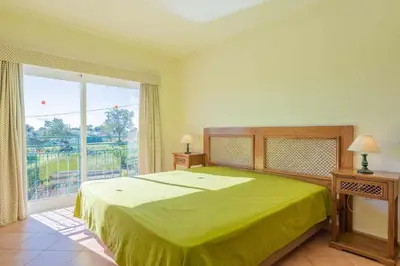 a bedroom with a green bed and a large window at Villa Água in Albufeira